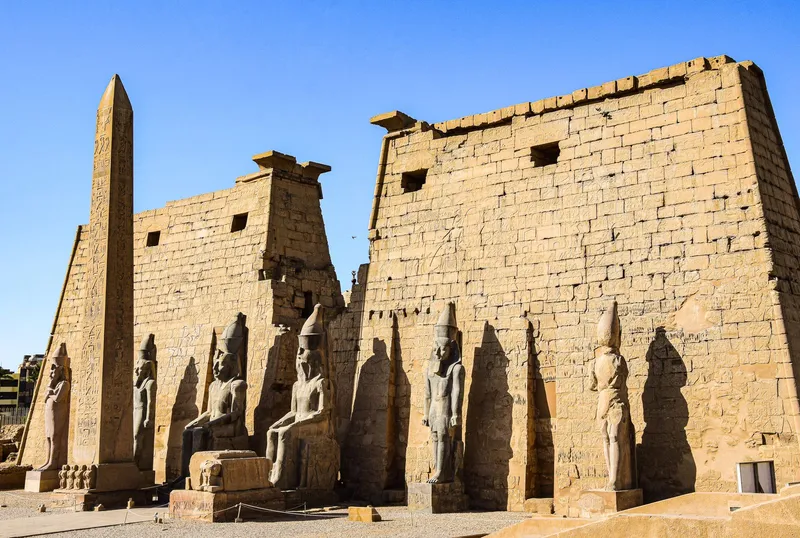 The first pylon of Luxor Temple with its obelisk and statues under a clear blue sky
