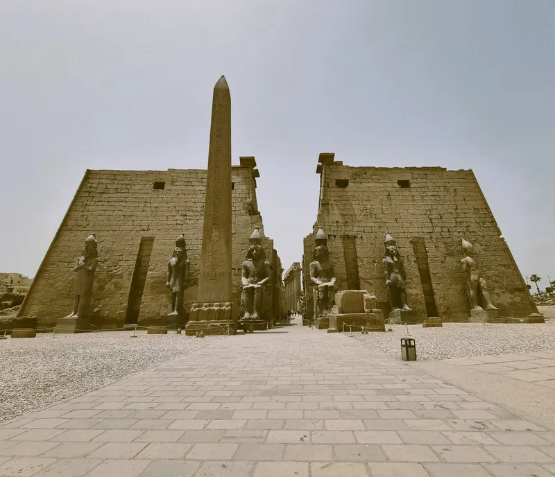 The paved approach to Luxor Temple's first pylon with its obelisk and statues on a hazy day