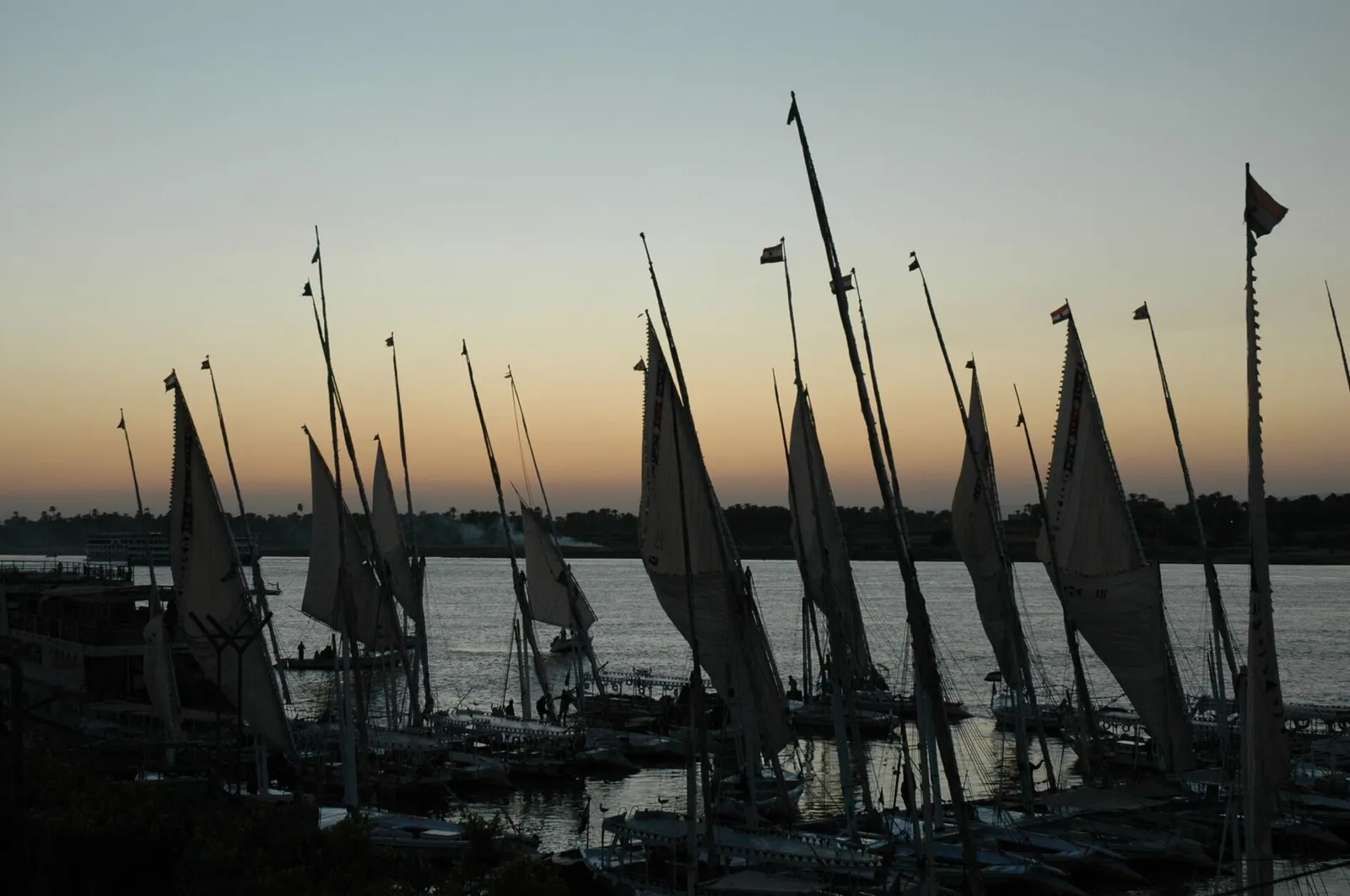 Moored felucca masts silhouetted against a sunset over the Nile
