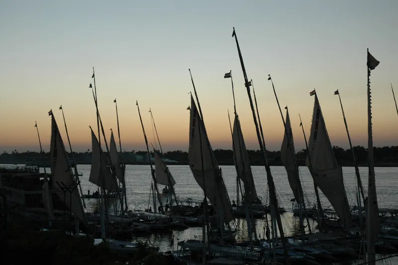 Moored felucca masts silhouetted against a sunset over the Nile