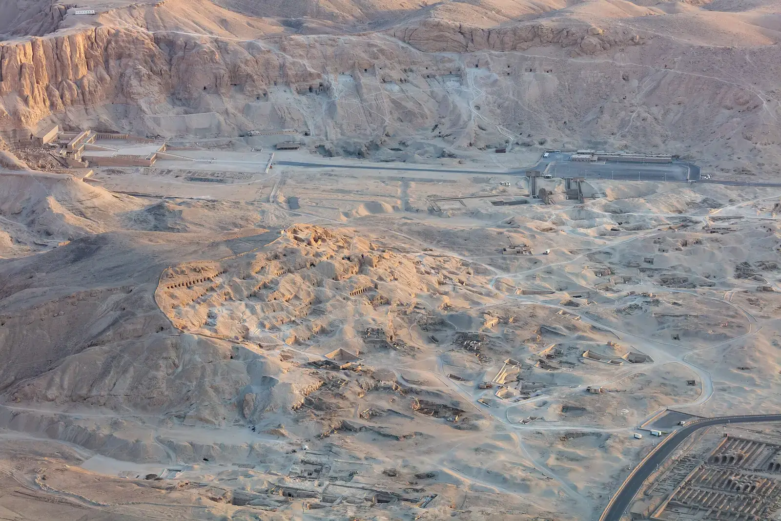 Aerial view at sunrise over the hill of the Tombs of the Nobles, rows of rock-cut tomb doors below the West Bank cliffs