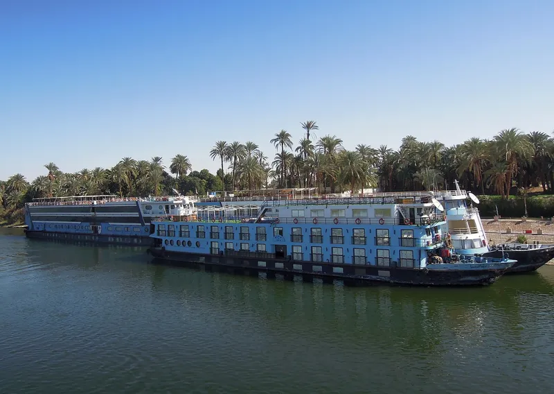 Nile cruise ships moored by a palm-lined bank