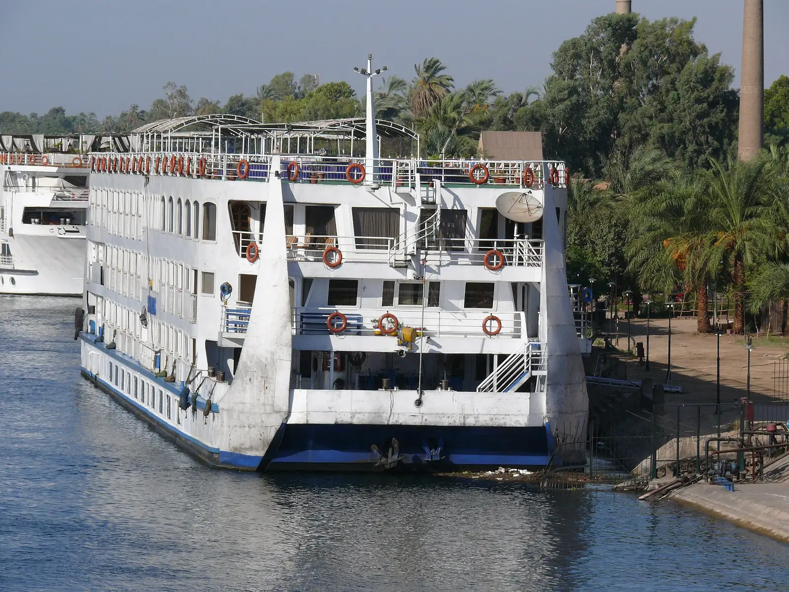 Stern of a cruise ship moored at a Luxor quay, palms behind