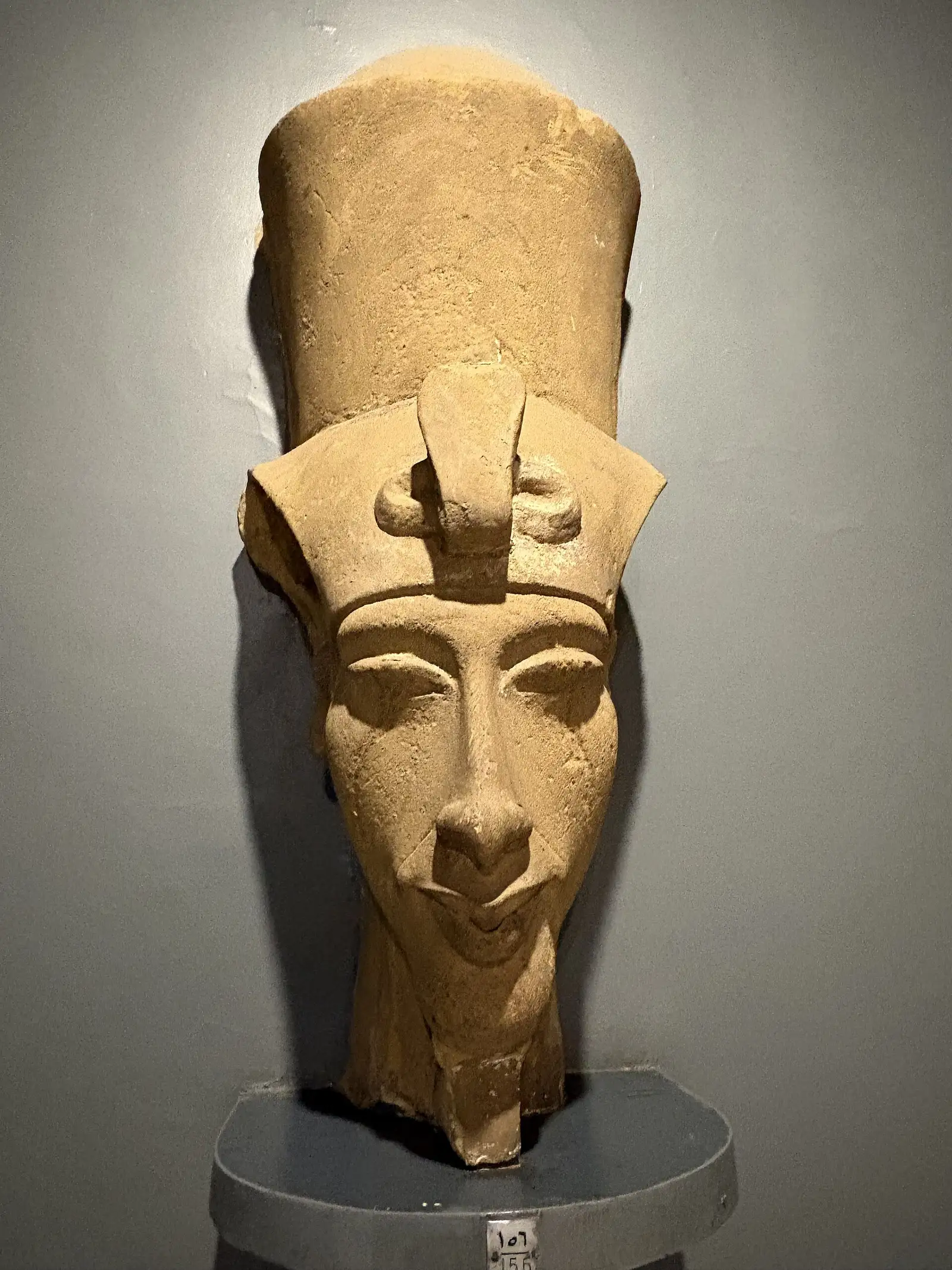 Sandstone head of Akhenaten with a tall crown on display in the Luxor Museum