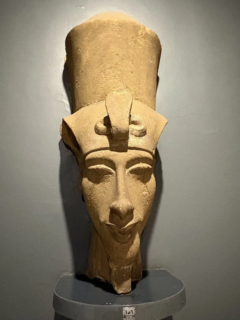 Sandstone head of Akhenaten with a tall crown on display in the Luxor Museum