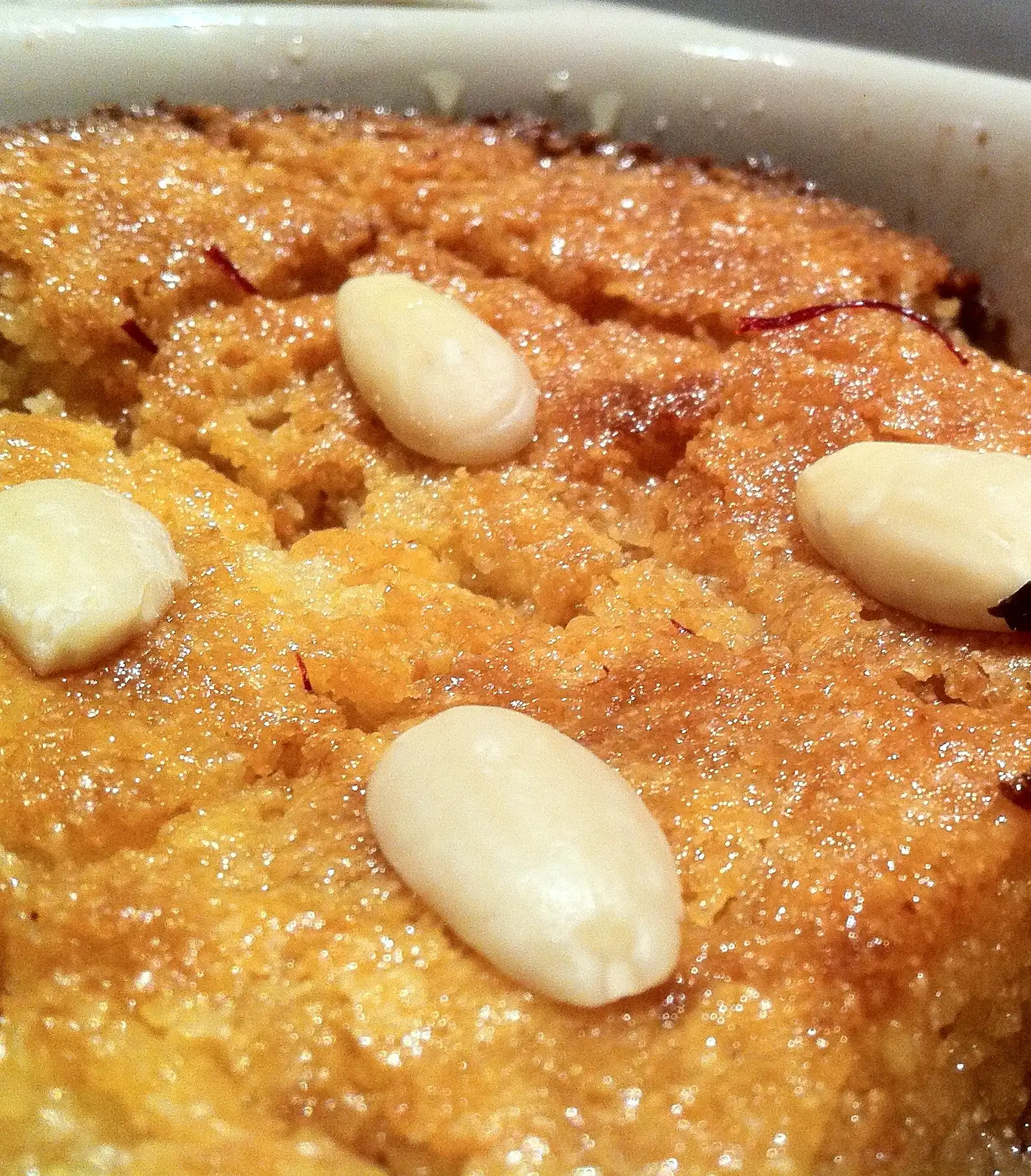Close-up of syrup-soaked basbousa topped with blanched almonds