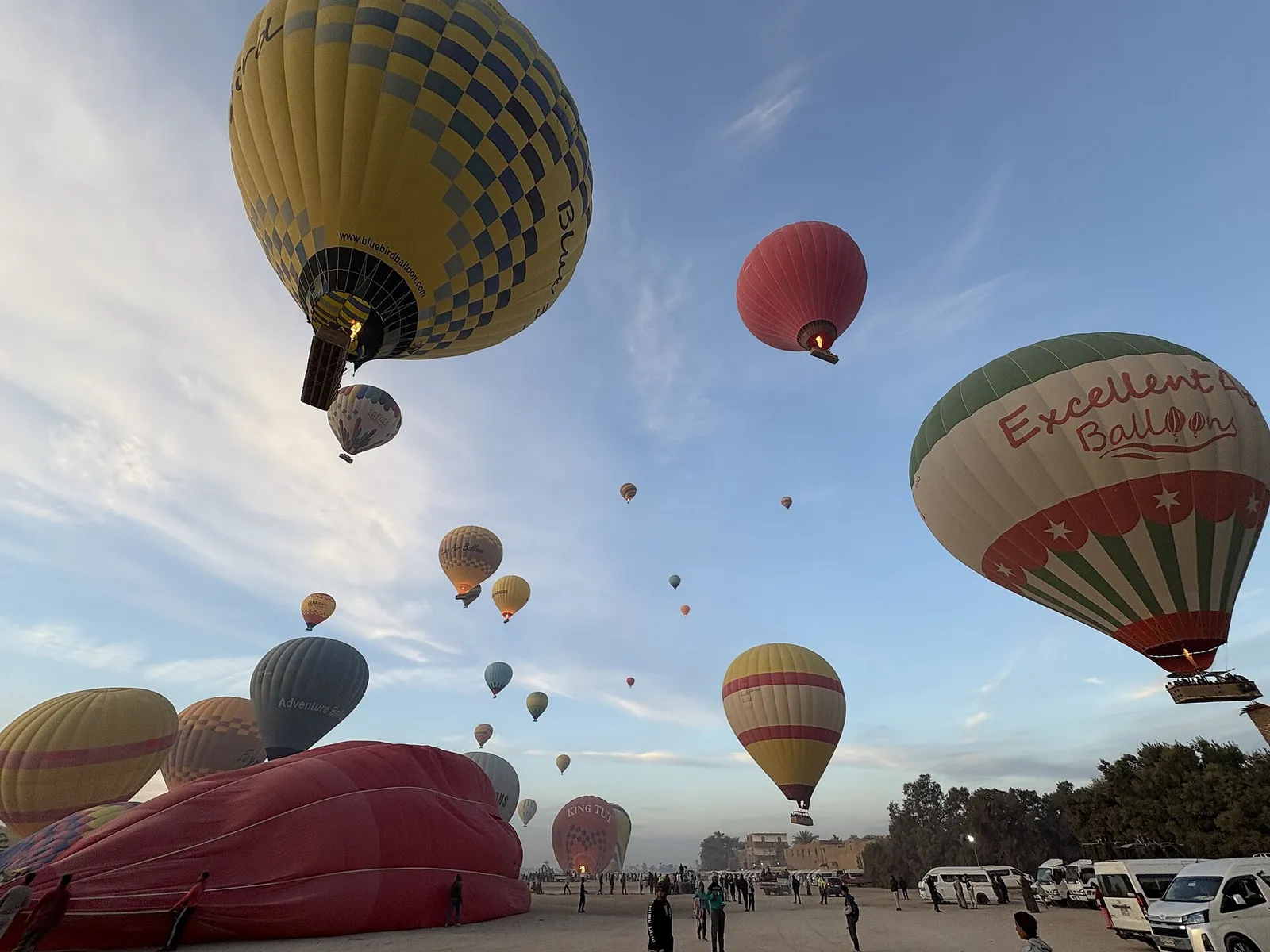 Balloons lifting off over the launch field at sunrise