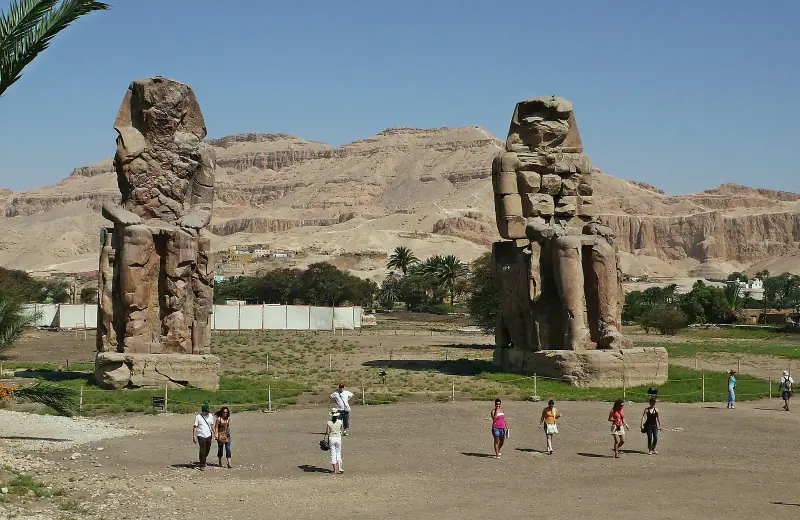 Both Colossi of Memnon with the Theban hills behind
