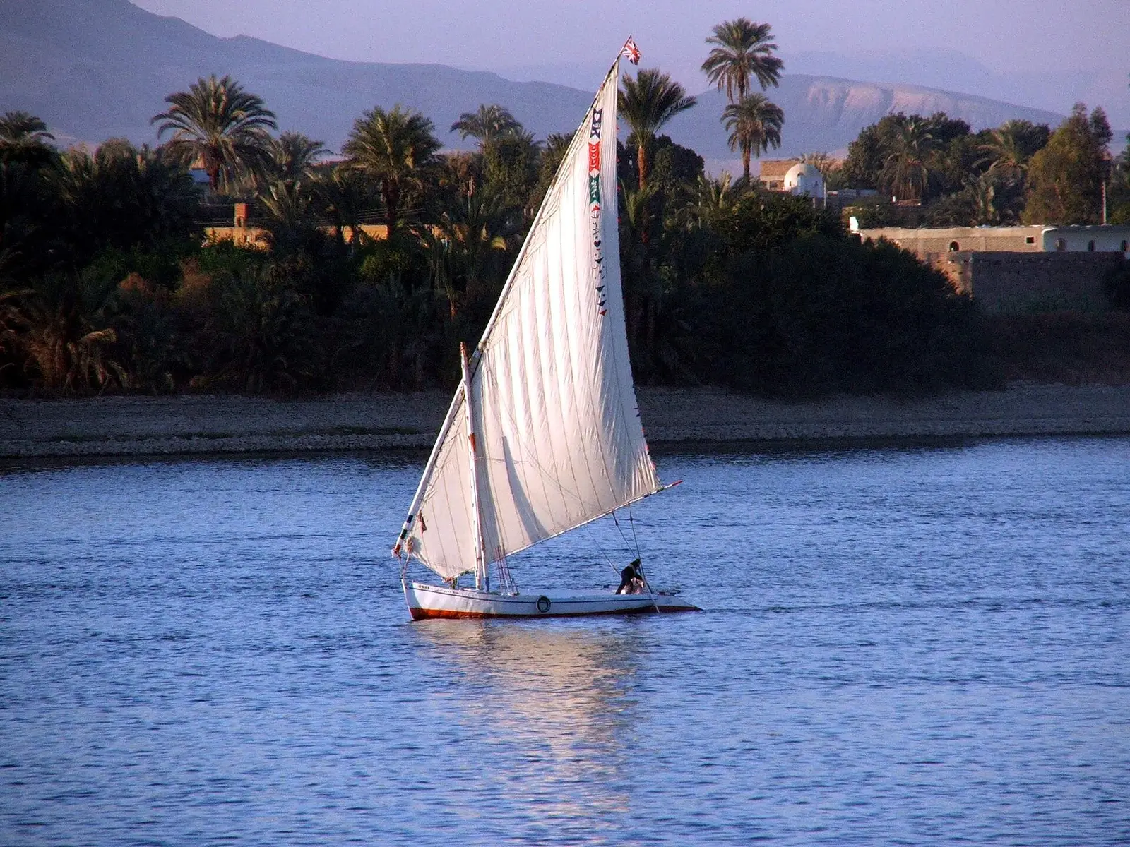 A single felucca sailing on the blue Nile at Luxor in evening light