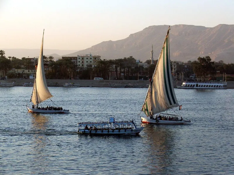Two feluccas and a river ferry crossing the Nile at Luxor in soft evening light
