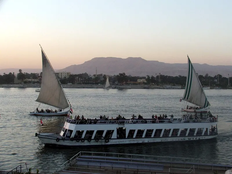 Feluccas and a crowded river ferry on the Nile at Luxor at dusk