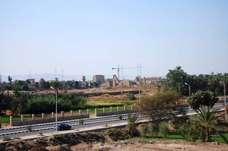 Distant view of Karnak's ruins beyond a road and palms