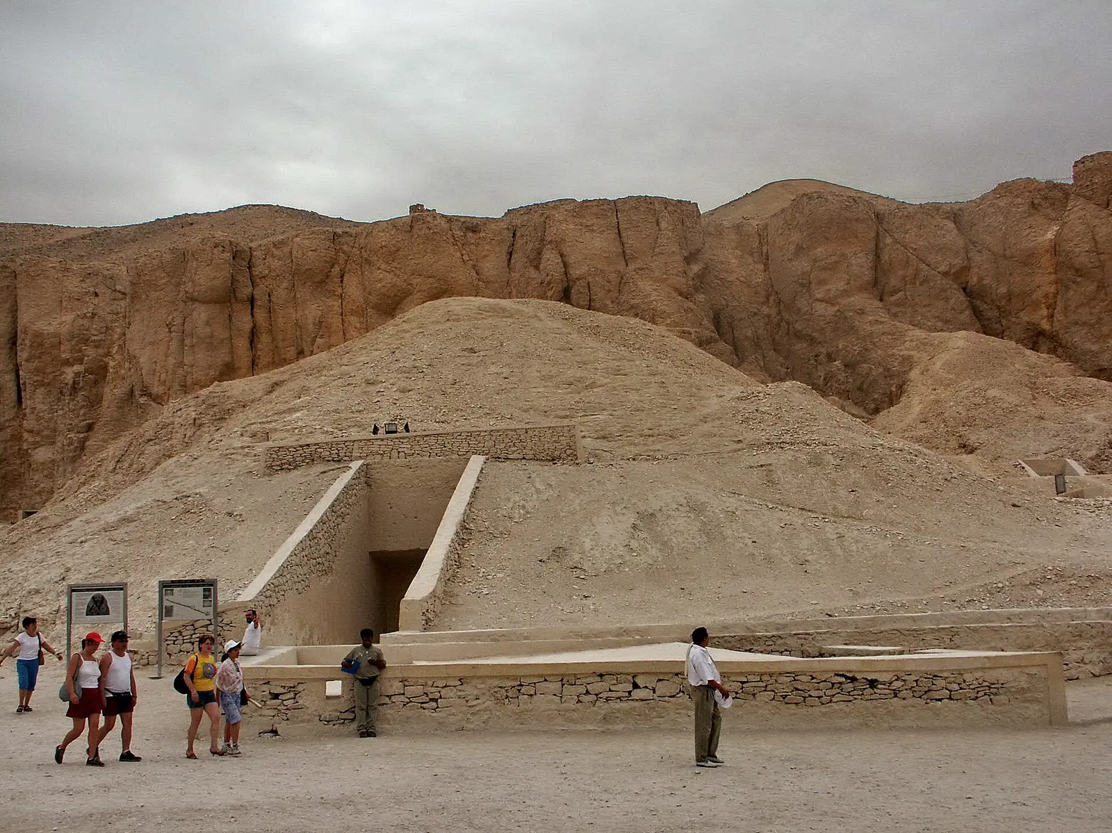 Walled entrance ramp of a tomb on the floor of the Valley of the Kings, visitors walking past