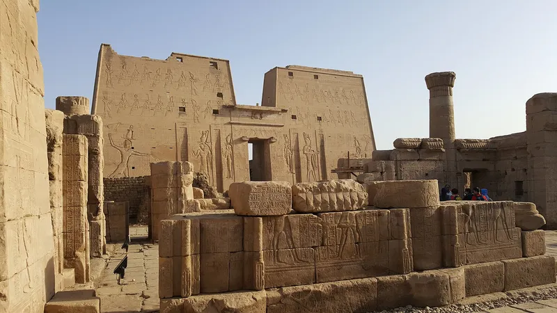 The carved pylon of Edfu temple behind fallen relief blocks in the late afternoon sun