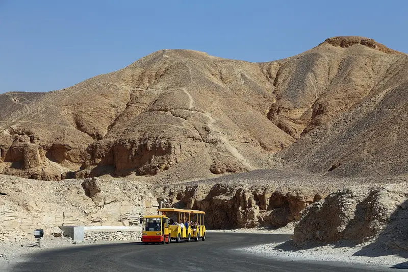 Yellow electric tram carrying visitors along the road into the Valley of the Kings