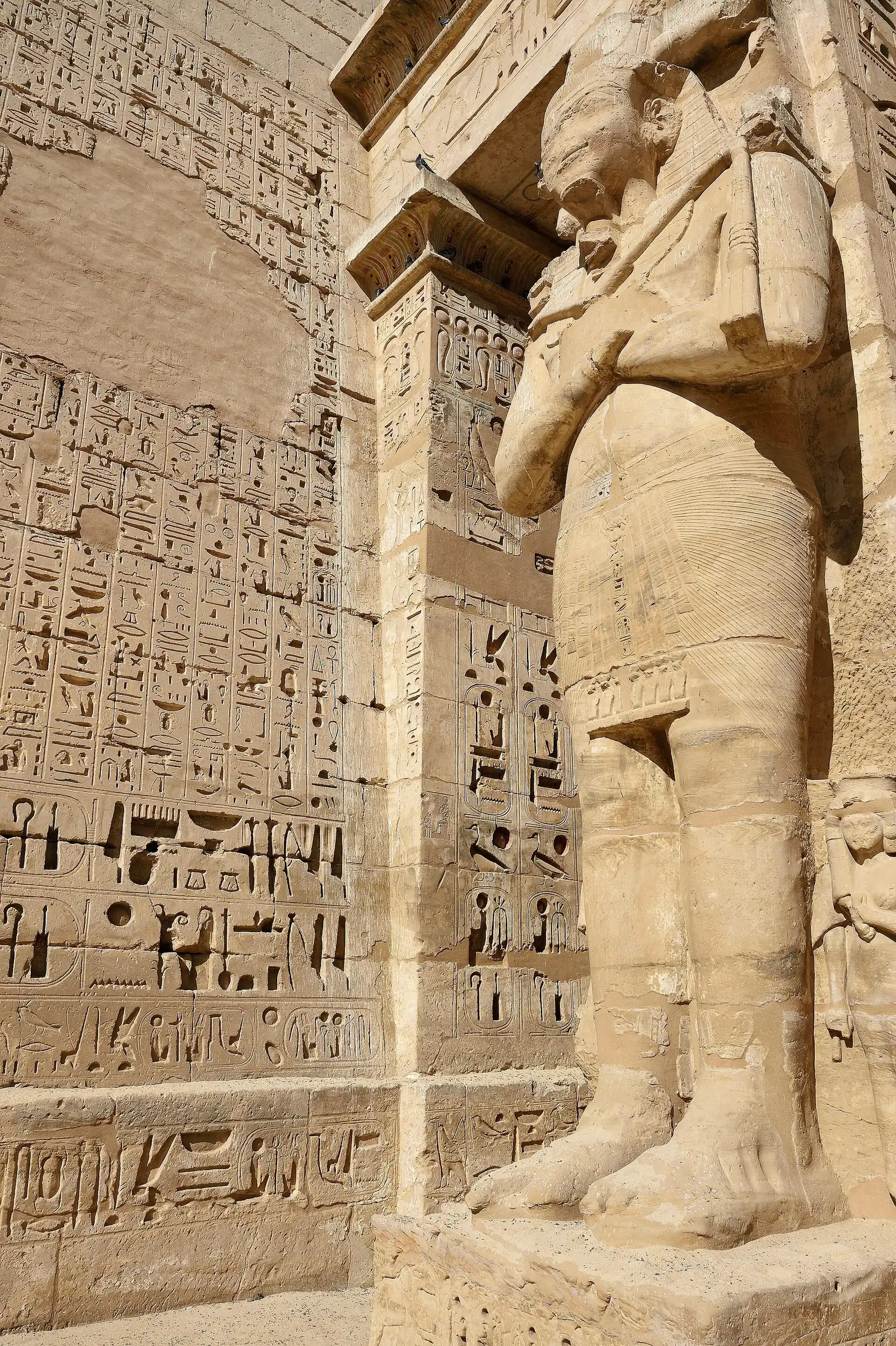 Carved Osiris statue of Ramesses III beside a wall of deep-cut hieroglyphs at Medinet Habu