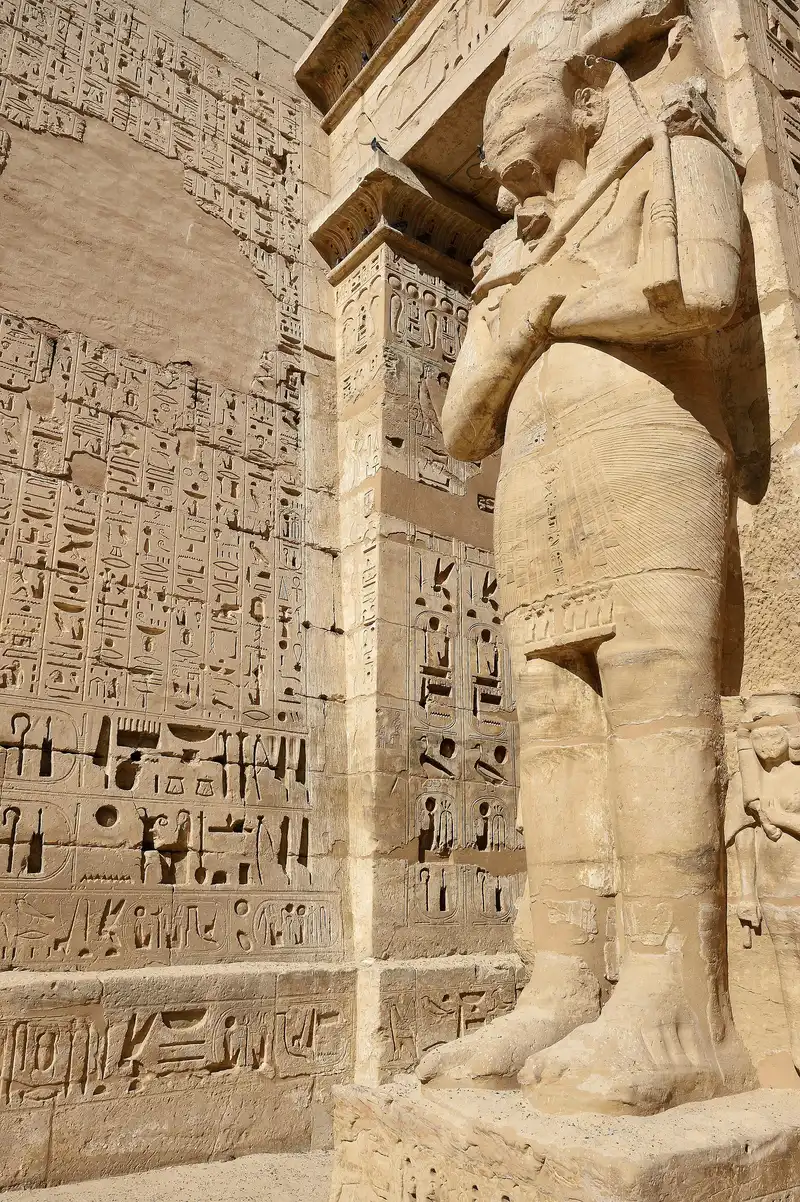 Carved Osiris statue of Ramesses III beside a wall of deep-cut hieroglyphs at Medinet Habu