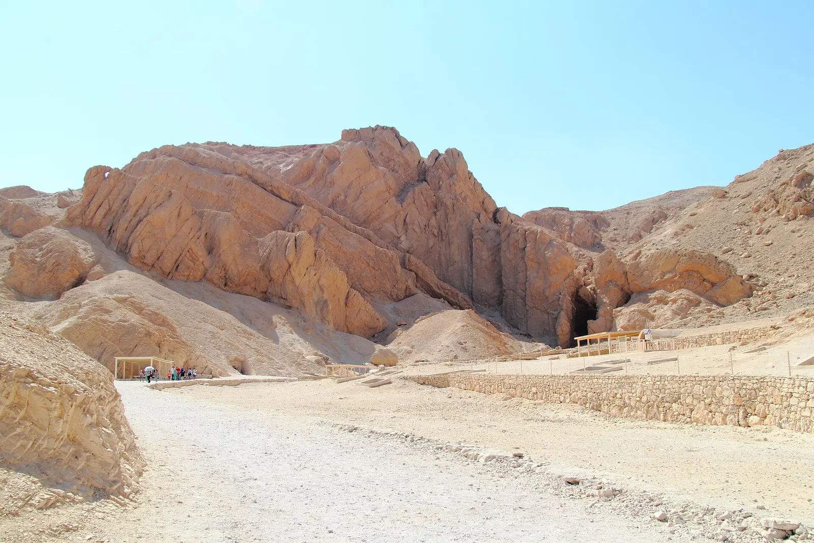 Paved path along a low stone wall toward tomb entrances in the Valley of the Queens